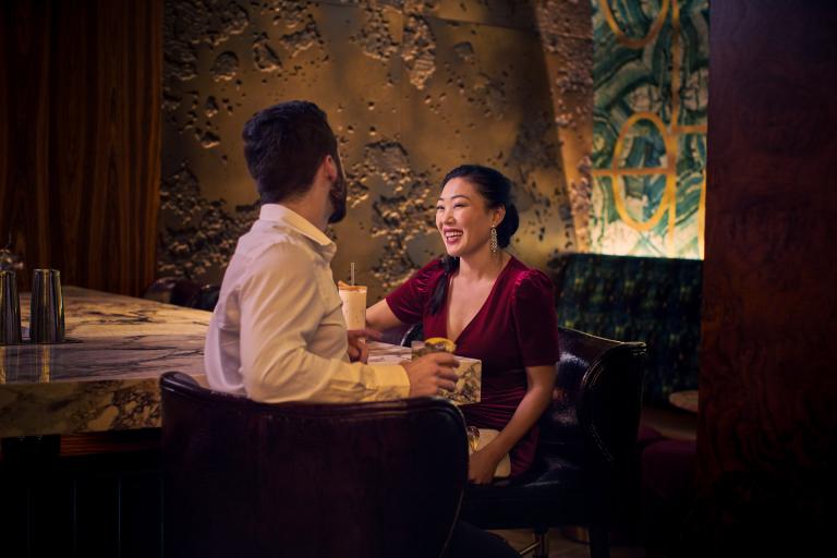 A well-dressed couple enjoys drinks at a marble bar