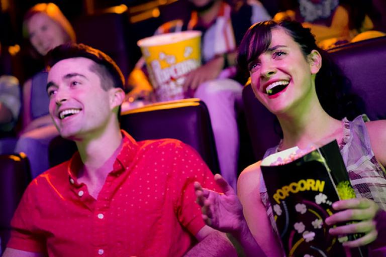 Couple in a movie theater, laughing and eating popcorn