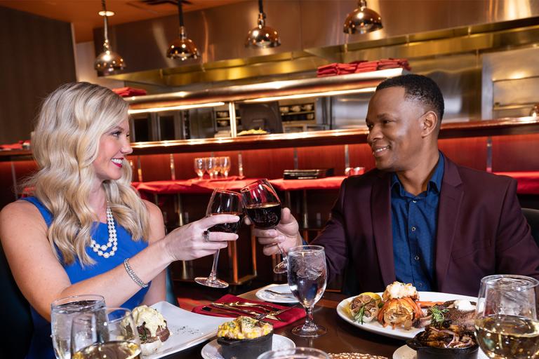 A couple is having a premium steaks with red wine. 
