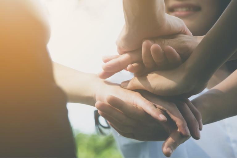 Cinematic view of three people holding and crossing their hands on top of one another