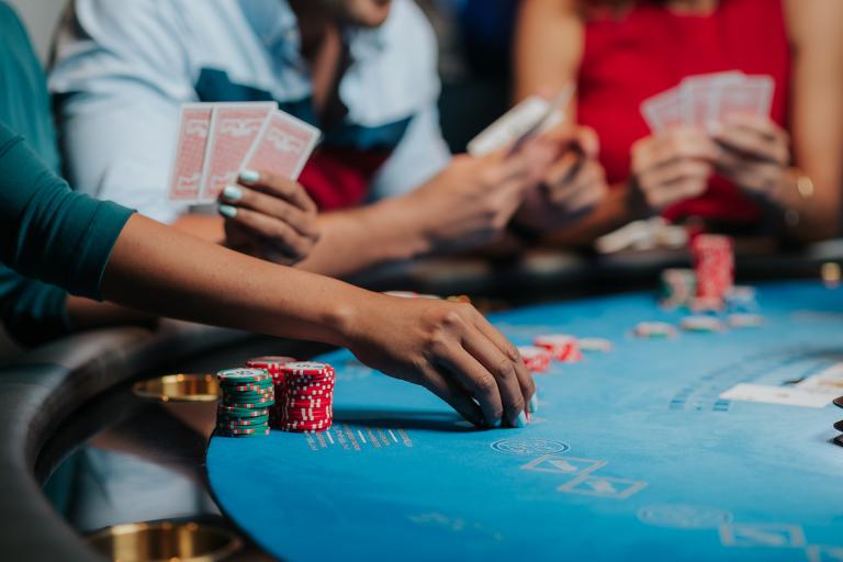 A woman placing chips down while two other people are looking at their hand of cards