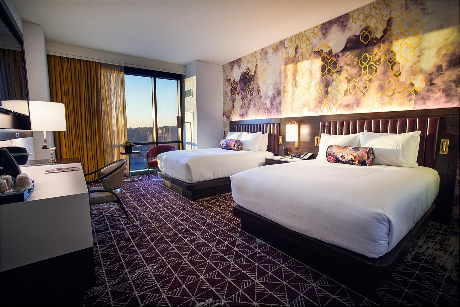 A modern hotel room with two queen beds, a flat screen TV and large window