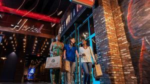 Three women exiting the Essentials gift shop with shopping bags in hand