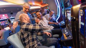 A group of four men sitting at slot machines congratulating each other on their wins