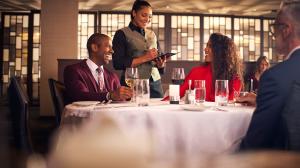 A waitress taking an order from a well dressed couple