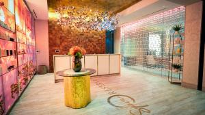 Luxurious spa with decorative glass walls, a wooden reception desk, a unique ceiling installation, and a central floral arrangement on a cylindrical table
