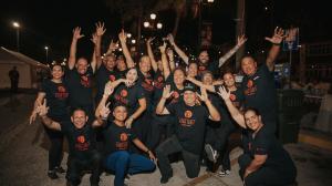 Group photo of people all wearing a black Long Table tee at night
