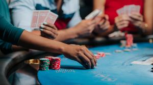 A woman placing chips down while two other people are looking at their hand of cards